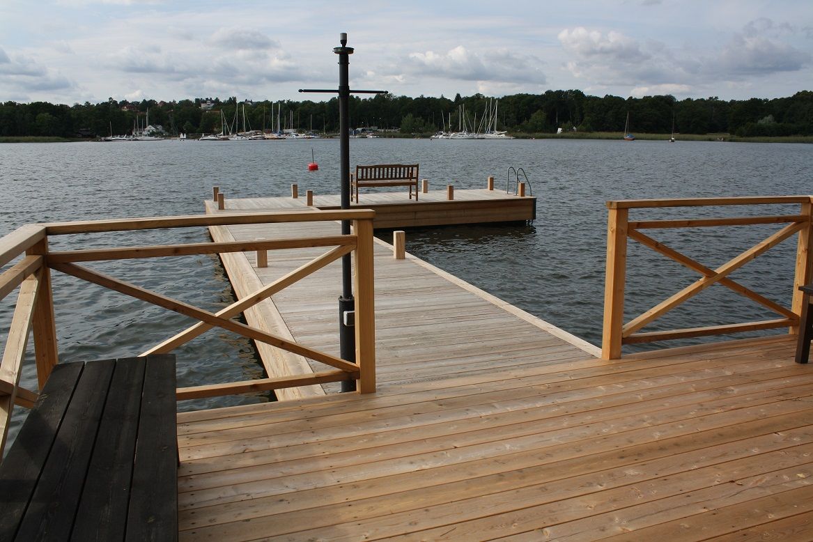 Wide calm harbour inlet with timber boardwalk and railing under an open sky